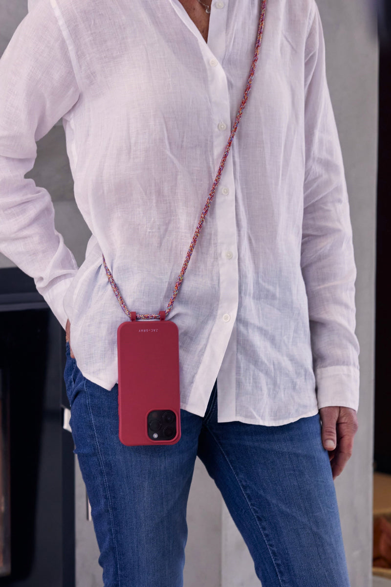 a woman in a white shirt is holding a red cell phone