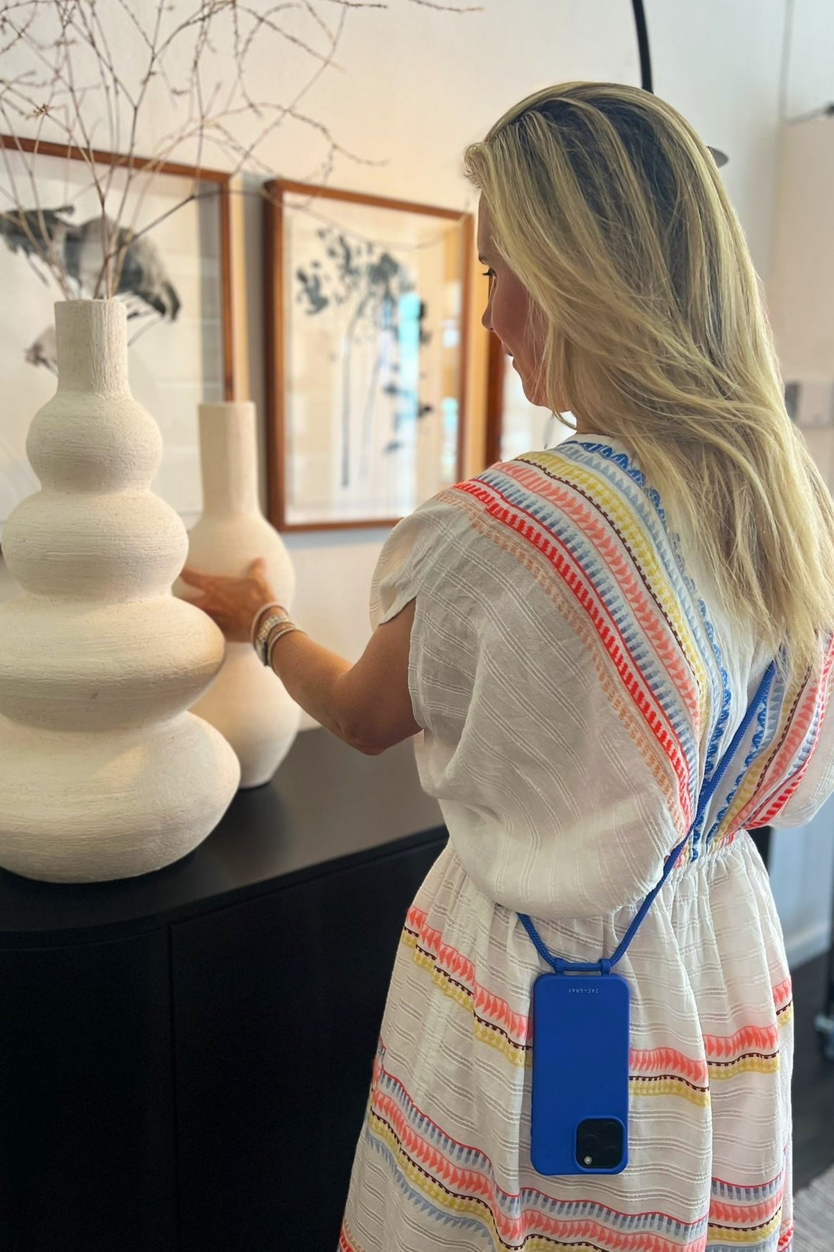 a woman in a white dress looking at a vase